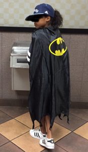 Young girl wearing Batman cape, seen from back